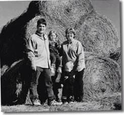 An early black and white photo of the Gunthorp family in front of round hay bales